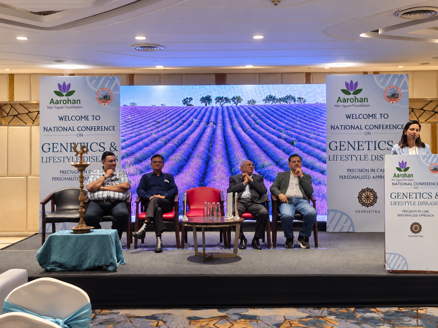 Panellists seated on the conference stage beside the ceremonial lamp